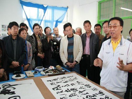 2012年10月4日,国庆长假的第四天,土生土长的125团走出去的知名人士曹永正(右一)先生回团欢度双节,现场为大家挥笔作诗一首。(据新疆兵团农七师网站)