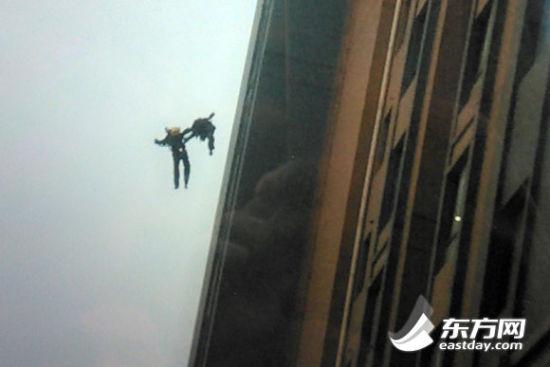 目击者王先生用手机拍下两位消防队员坠楼时的画面,图上可以看出,两消防员坠楼瞬间手拉着手