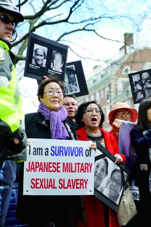 资料图:4月27日,在美国马萨诸塞州的哈佛大学肯尼迪政府学院外,抗议者手举标语,要求日本首相安倍晋三就“慰安妇”等日本二战罪行道歉。 新华社发